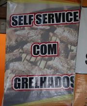 Cartaz de restaurante: "Self service com grelhados" sobre imagem de carnes grelhadas.