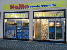 Schaufenster eines Bodenbelagstudios mit Laminat- und Vinyl-Design und gelbem Firmenschild.