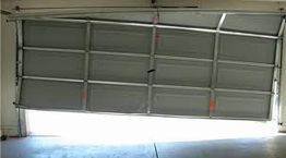 Bent garage door partially open, misaligned with damage.