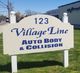 Sign for 123 Village Line Auto Body & Collision on a grassy area by the roadside.