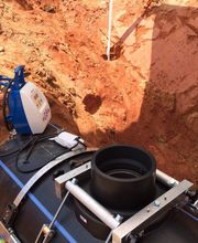 Equipamento de fusão em tubo de plástico, em terreno de terra vermelha, usado em obras subterrâneas.