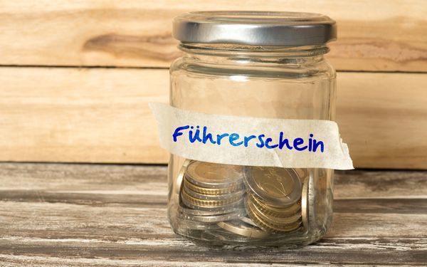 Ein Sparglas mit der Aufschrift "Führerschein". Eine Person spart auf ihren Führerschein.