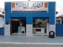 Loja de móveis com fachada azul e letreiro "Cabral Móveis: Qualidade e Bom Preço".