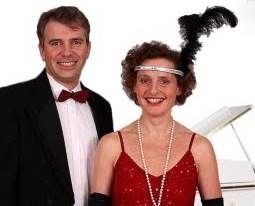 Paar in eleganter Abendkleidung, Frau trägt ein rotes Kleid und Federaccessoire.