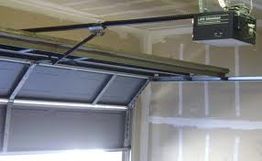 Garage door mechanism with ceiling-mounted opener in a partially open position.