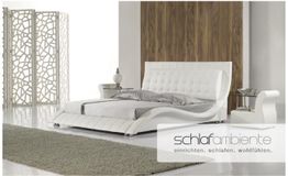 Schlafzimmer mit modernem weißen Bett, Zierlampe, Holzpaneelwand und Teppich auf weißem Boden.