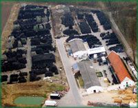 Luftaufnahme eines Industriegeländes mit vielen gestapelten schwarzen Materialien und mehreren Gebäuden.