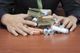 Person in a suit holding stacks of cash and coin rolls on a wooden table.