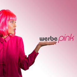 Frau mit pinker Perücke zeigt auf „werbe pink“ Schriftzug vor rosa Hintergrund.