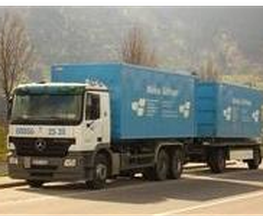 LKW mit blauem Container vor Landschaft geparkt.