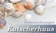 Muscheln und Schriftzug „Ferienwohnungen Kutscherhuus“ auf hellem Hintergrund.