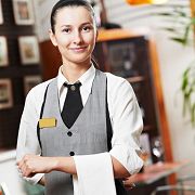Young waiter in uniform with a towel, standing in a restaurant.