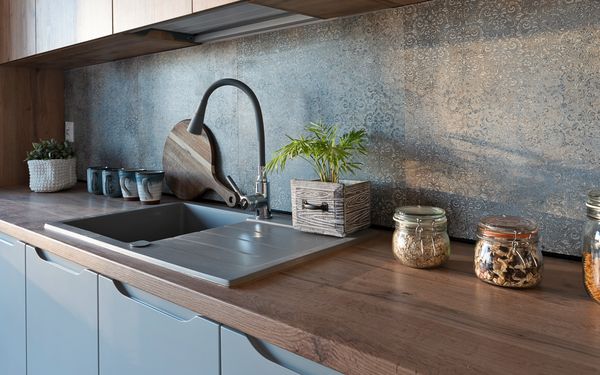 Encimera de cocina de madera con fregadero integrado, grifo moderno y salpicadero decorativo en una cocina contemporánea