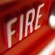 Close-up of a red fire alarm button with the word "FIRE" in white letters.