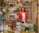 Eine Frau steht in einem Laden mit Dekorationsartikeln und Produkten auf Regalen und Tischen.