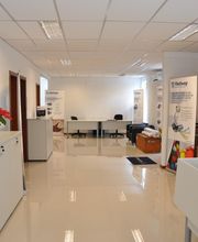 Escritório moderno com móveis brancos, plantas e cartazes nas paredes. Ambiente organizado.