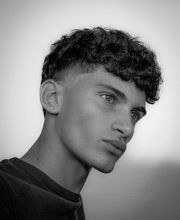 Giovane uomo di profilo con capelli ricci in bianco e nero.