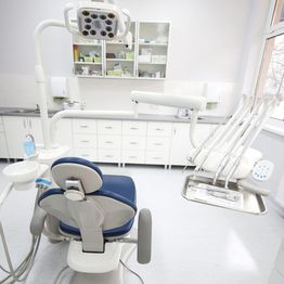 Dentist office with chair, overhead light, and tools in a clean, bright room.