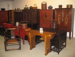 Antike asiatische Holzmöbel und Dekorationen stehen in einem Raum ausgestellt.