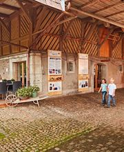 Eine Gruppe Menschen sitzt draußen in einem Bauernhofcafé, während andere vorbeigehen.