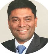 Smiling man in a suit and tie, circular portrait.