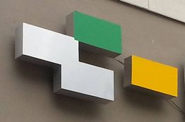 Logo con bloques en verde, blanco y amarillo en la fachada de un edificio.