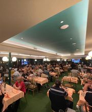 Persone mentre cenano in un grande ristorante affollato con soffitto azzurro.