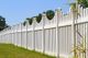 White picket fence with decorative tops against a clear blue sky and grassy foreground.