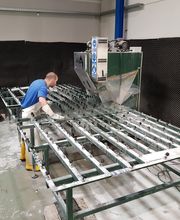 Person arbeitet an einer großen Metallmaschine in einer Werkstatt.