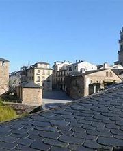 Vista de una ciudad con casas antiguas y una torre sobre un cielo azul despejado.