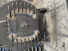 Rundes Metallgerät mit Schrauben und Schweißnähten, auf einer Werkbank montiert.