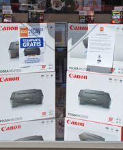 Scatole di stampanti Canon PIXMA in una vetrina con cartelli promozionali.