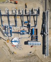 Luftaufnahme einer Baustelle mit Maschinen, Kränen und Gebäudestrukturen.