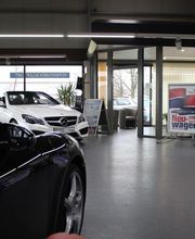 Autohaus-Showroom mit einem schwarzen und einem weißen Auto, umgeben von Verkaufsschildern.