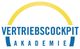 Logo der VertriebsCockpit Akademie mit gelbem Halbkreis und blauem Text.