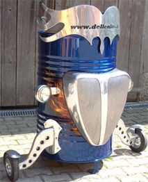 Blauer Metallbehälter mit dekorativen Chromteilen und Rädern, steht auf einem gepflasterten Boden.