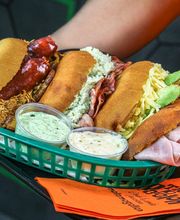 Cuatro arepas variadas en una bandeja con salsas en pequeños recipientes.