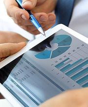 Tablet zeigt Diagramme; zwei Hände bei einer Besprechung mit Stift.