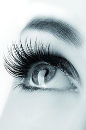 Nahaufnahme eines Auges mit langen Wimpern und detaillierter Iris in Schwarz-Weiß.