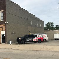 Two utility vans parked beside a brick building under a cloudy sky.