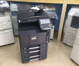 Stampante multifunzione nera in una stanza con pavimento piastrellato e altre stampanti.