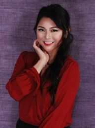 Woman in red blouse smiling with hand on chin, purple background.