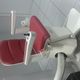 Sedia motorizzata per scale con rivestimento rosso, su binario curvo, in un ambiente chiuso.