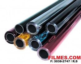 Rolos de filme plástico coloridos empilhados em um fundo branco.