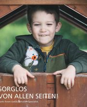 Junge lächelt spielend in einem Holzhaus. Text: "SORGLOS VON ALLEN SEITEN!"