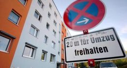 Verkehrsschild: 20 m für Umzug freihalten, vor einem mehrstöckigen Wohngebäude.