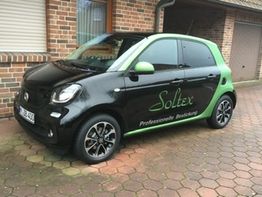 Schwarzer Kleinwagen mit grünem Akzent und "Soltex" Schriftzug auf gepflasterter Einfahrt.