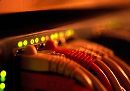 Nahaufnahme von Netzwerk-Kabeln und leuchtenden LEDs an einem Router in warmem Licht.