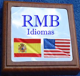 Placa de madeira com texto "RMB Idiomas" e bandeiras da Espanha e dos EUA.