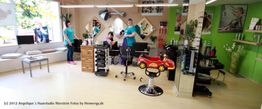 Friseursalon mit Kinderstuhl in Form eines Autos, Spiegeln und Friseurinnen bei der Arbeit.